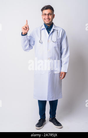Full body shot of happy Persian man doctor pointing up Stock Photo