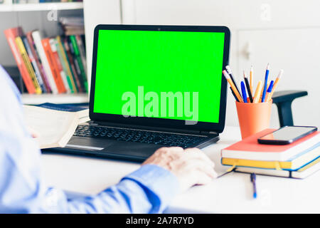 Close-up of hand man using a mouse and typing on green screen laptop on white table, business concept Stock Photo