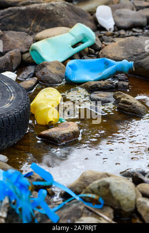 Plastic bottles old tire and styrofoam in dirty water. Global enviromental pollution problem. Stock Photo
