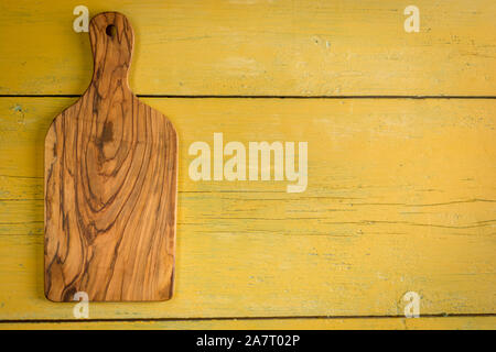 Olive wood cutting board on yellow rustic background with copy space. Flat lay. Stock Photo