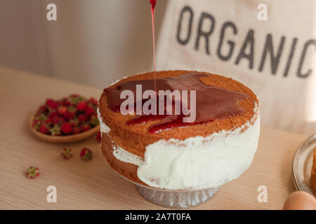 fresh sponge cake with raspberry syrup being poured over the top. Making red velvet or sponge cake process Stock Photo