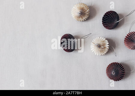 Christmas styled stock composition. Decorative white and crimson paper Christmas ornaments on grey table linen background. Flat lay, top view, winter Stock Photo