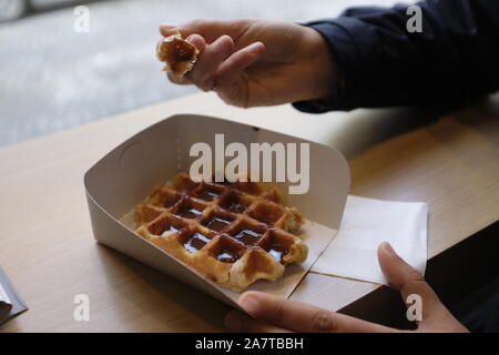 eating a chocolate waffle on paper in Belgium Stock Photo