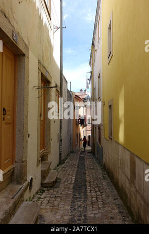 Lisbon, Portugal 16 April 2019: A tourist walking down a narrow alleyway in the old town of Lisbon, Portugal Stock Photo