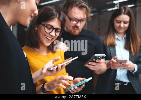 Group of positive business people working together and using modern smartphone at office. Digital gadgets using concept Stock Photo