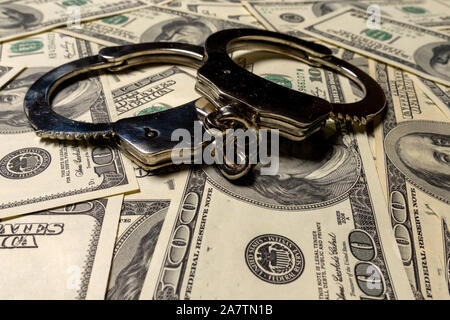 Handcuffs on hundred dollar american banknotes. The concept of corruption, robbery, fraud. Side view Stock Photo