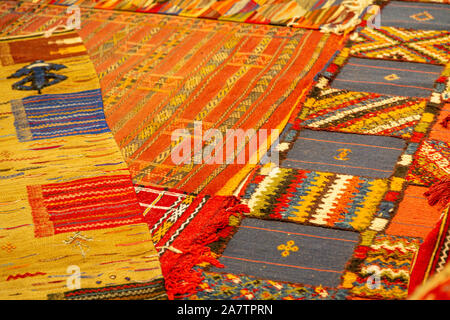 closeup of assortment of Moroccan carpets resting on the ground in a souk Stock Photo