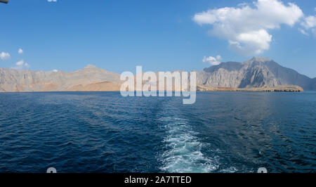 Panorama from the back of a Dhow Boat looking to the Fjords, beautiful blue water, mountains and clouds of Musandam, Oman in the Middle East. Stock Photo