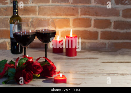 Romantic evening in red colores with wine, roses and candles. St. Valentine's Day or engagement concept. Stock Photo