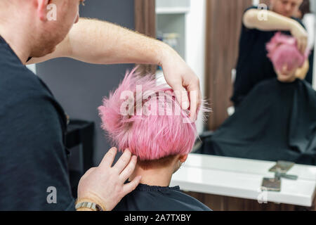 Hands Of Hairdresser Checks Short Pink Hair Of Girl On Gray
