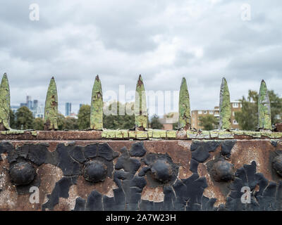 Green metal spikes against the sky on top of a metal barrier Stock Photo