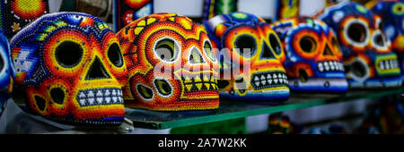 Panoramic image of colorful day of the dead (Dia de los Muertos) skulls on display in a street market. Selective focus Stock Photo