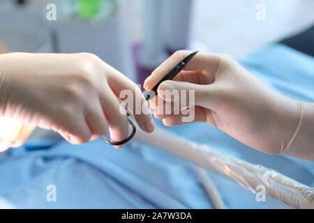 The hands of the dentist and the assistant in protective gloves with the instrument in the treatment of the patient Stock Photo