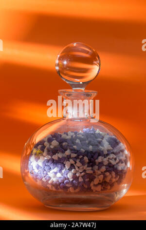 glass jar with ball cap, full of colored pebbles, centered on an orange background Stock Photo