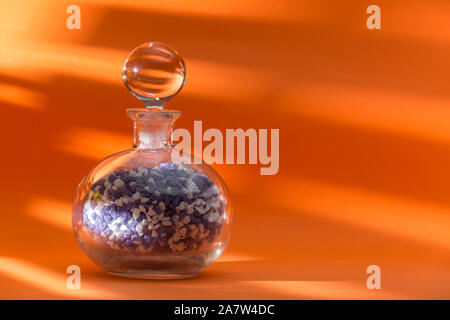 glass jar with ball cap, full of colored pebbles, centered on an orange background Stock Photo