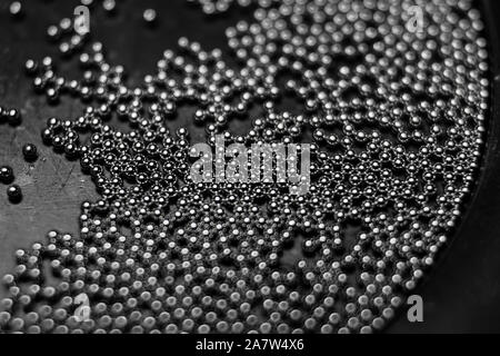 Close-up of industrial electronics assembly manufacturing materials RoHS 0.6mm round BGA soldering balls in partial focus randomly scattered on a blac Stock Photo