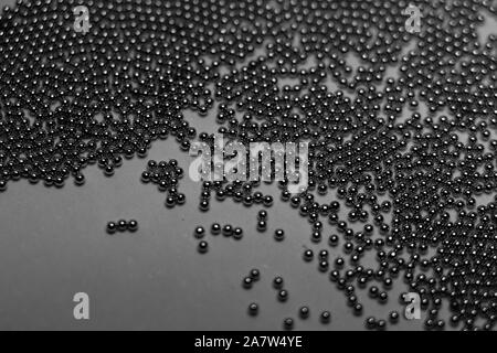 Close-up of industrial electronics assembly manufacturing materials RoHS 0.6mm round BGA soldering balls in partial focus randomly scattered on a gray Stock Photo