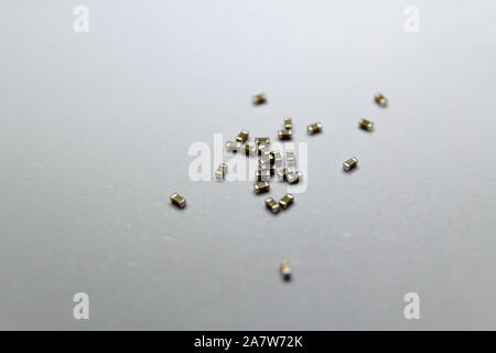Close-up of scattered 0201 SMT ceramic film capacitor power electronics components on white background in random pattern Stock Photo