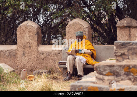 AXUM, ETHIOPIA, APRIL 27.2019, Resting orthodox priest in front of old cathedral of Our Lady of Zion on April 27, 2019 in Aksum, Ethiopia, Africa Stock Photo