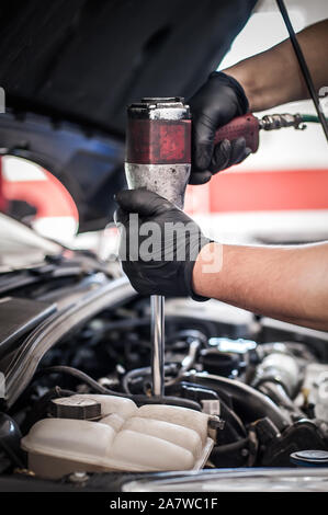 Car master mechanic repairer checking, testing and changing spark plugs on the car in auto vehicle workshop Stock Photo