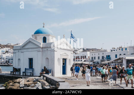 Mykonos Town, Greece - September 23, 2019: People walking past Agios Nikolakis Church in new port in Hora, also known as Mykonos Town, the capital of Stock Photo