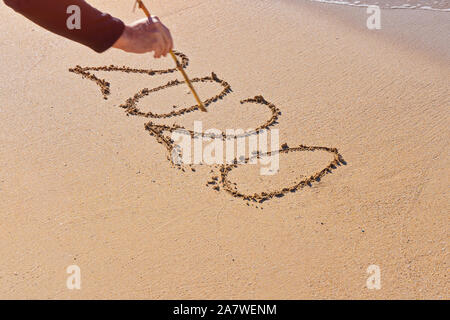 Numbers 2020 written by man on sandy seashore beach. Lettering with 2020 for celebrating New Year. Happy new year symbol. Abstract art. Stock Photo
