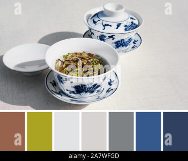 Trendy color matching palette with natural green, grey and blue color shades  from close-up on two white and dark blue ceramic cups of traditional whi