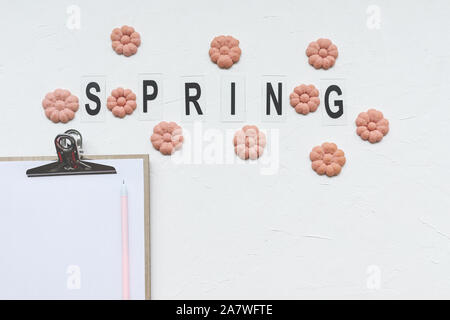 SPRING word and flower cookies, paper and pen on a white background. Spring holidays cooking and To Do list concept. Top view, flat lay, mockup, socia Stock Photo