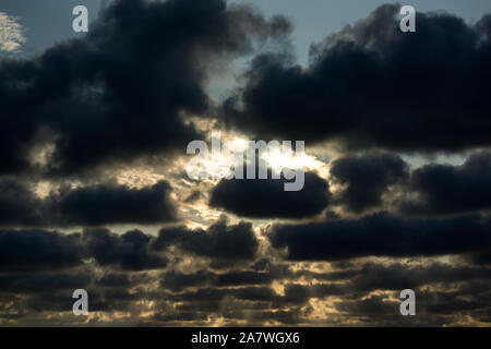sun hidden behind dark altocumulus clouds Stock Photo