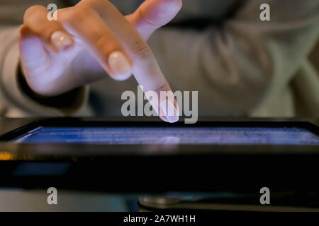 Woman hand using touchscreen display of floor standing black tablet kiosk Stock Photo