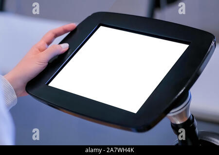 Close up view: woman using floor standing tablet kiosk with blank white display Stock Photo