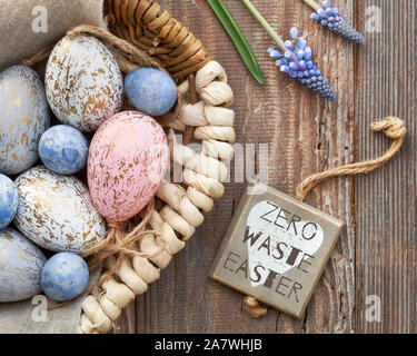 Easter background with eggs, blue hyacinth flowers and wooden heart, top view on rustic wood. Zero waste Easter written on wooden tag with heart. Eco Stock Photo
