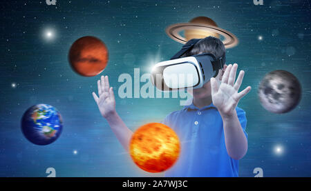 Planets revolve around boy with virtual reality glasses. Concept of using modern technologies for learning and fun. Stock Photo