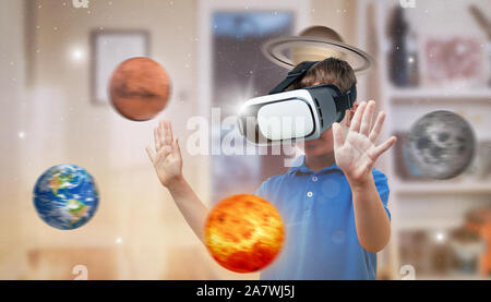 Boy with a virtual reality headset exploring planets in his room. The concept of using modern technologies for education. Stock Photo