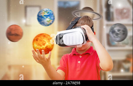 Boy with virtual reality glasses holds the Sun  in his room. Concept of using modern technologies for learning. Stock Photo
