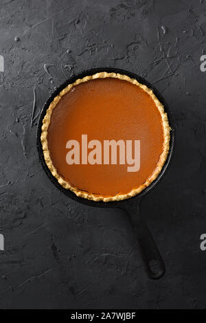 Homemade open pumpkin pie in cast iron pan on black background top view copy space overhead view Stock Photo