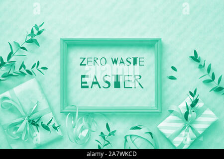 Flat lay monochrome image toned in trendy biscay green color. Text 'Zero Waste Christmas' in wooden frame. Flat lay background with wrapped gift boxes Stock Photo