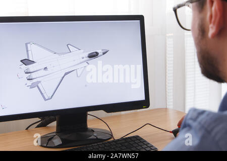 Engineer, Constructor, Designer in Glasses Working on a Personal Computer. He is Creating, Designing a New 3D Model of Aircraft, Airplane in CAD Progr Stock Photo
