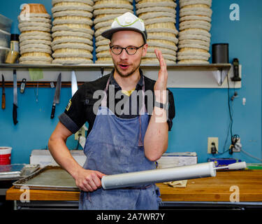 A professional baker talks with rolling pin in hand in kitchen Stock Photo