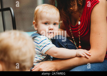 Cute baby boy holding onto mother's arms Stock Photo