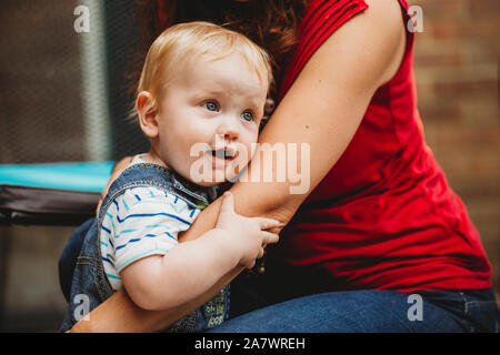 Cute baby boy holding on to mother's arm Stock Photo