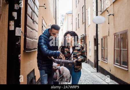 couple laughing together whilst cycling with their dog in the basket Stock Photo