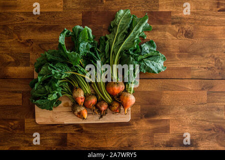 fresh beets on cutting board set on wooden table viewed from above Stock Photo