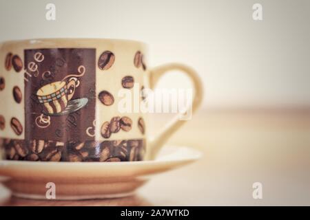 Coffee game part, cup on plate in vertical plane with coffee drawings. Stock Photo