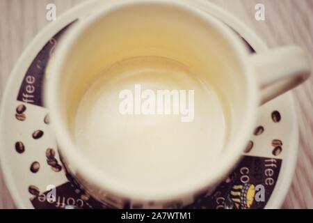 Aerial shot of coffee cup on plate with drawings of coffee beans Stock Photo
