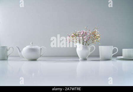 Composition with white porcelain tea-ware on a light gray background with a delicate bouquet of flowers Stock Photo
