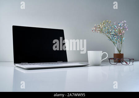 Composition with a modern laptop, a white cup and other vintage things with a delicate bouquet of flowers on a light gray background Stock Photo