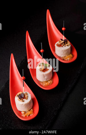 Goose liver pate, foie gras, served on black stone in Japanese red spoons. Paste served with jam and nuts. Fusion food concept, low key, copy space Stock Photo