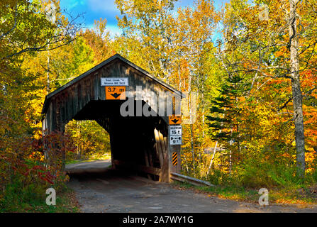 An autumn landscape image  of an iconic covered bridge crossing Trout Creek on a rural gravel road near Sussex  New Brunswick Canada. Stock Photo