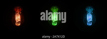 Retro looking light bulb glowing on dark background, bright wire visible in glass - colour can be changed with hue saturation tool Stock Photo